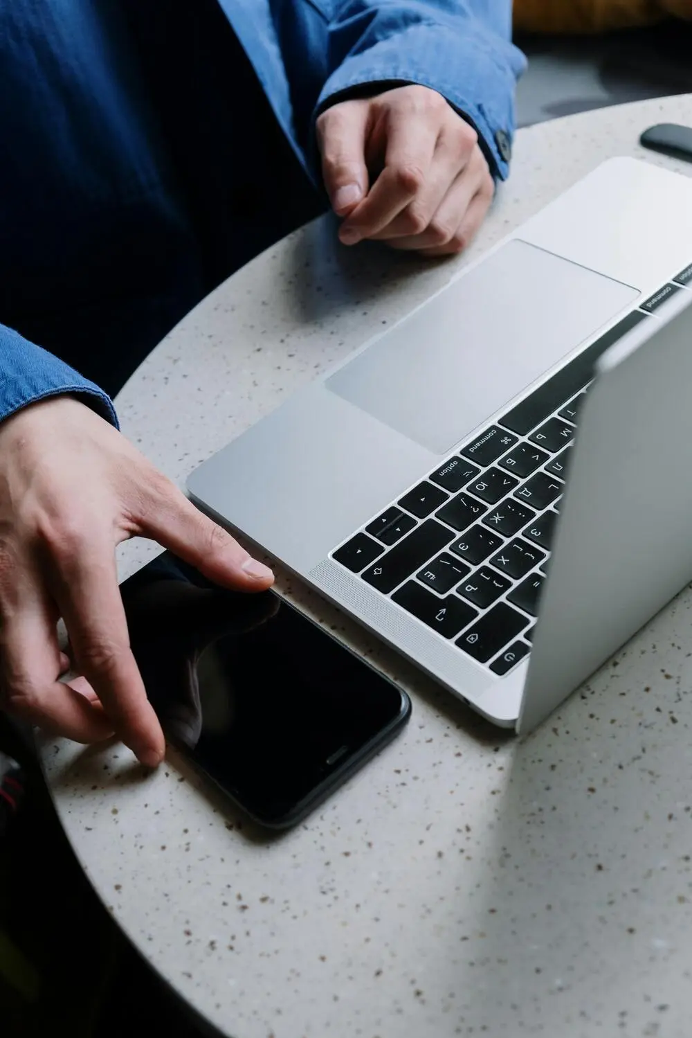 men's hands with a cell phone and laptop